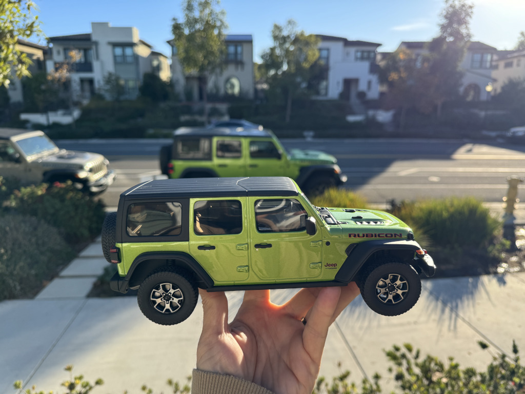 Model Jeep Wrangler held up in front of the real thing.